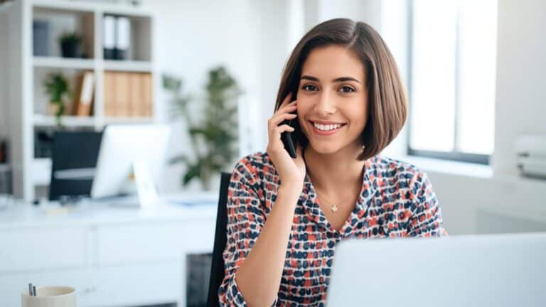 Junge Frau telefoniert lächelnd im Büro – Symbolbild für Beratung durch das Kompetenzteam zur privaten Krankenversicherung (PKV).